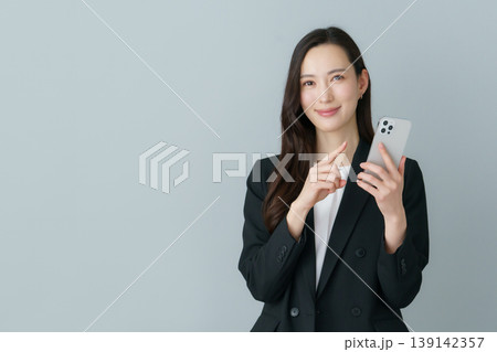 グレーバックのスマホを持つ若いスーツの日本人女性 グレーバックのスマホを持つ若いスーツの日本人女性 139142357