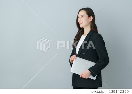 グレーバックのノートパソコンを持つ若いスーツの日本人女性 グレーバックのノートパソコンを持つ若いスーツの日本人女性 139142390