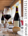 Glass of Red Wine and Bottle on Restaurant Table with Bread and Glassware 139145321