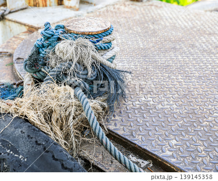 Mooring line on rusty pier referred to a post on a ship or quay. Mooring line on rusty pier referred to a post on a ship or quay. 139145358