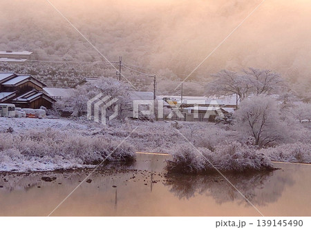朝焼けに染まる雪の里山風景　川面に映る静寂の冬景色 139145490