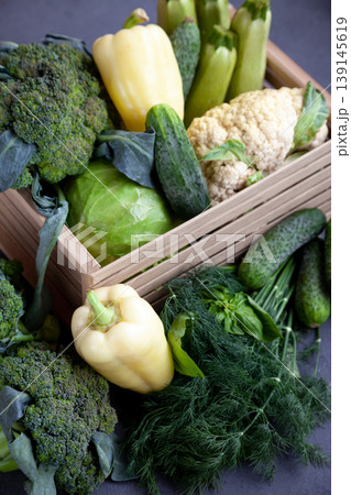 Vegetable basket. Fresh vegetables on the table black background. Set of food delivery box. Broccoli, cabbage, eggplant, white cabbage, cucumber, dill, cauliflower. Stilllife top view. Vegetable basket. Fresh vegetables on the table black background. Set of food delivery box. Broccoli, cabbage, eggplant, white cabbage, cucumber, dill, cauliflower. Stilllife top view. 139145619