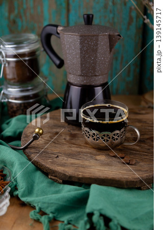 Brewed Espresso in Vintage Glass Cup with Geyser Coffee Maker on Rustic Wooden Board Background. Drink in old metal cup holder Brewed Espresso in Vintage Glass Cup with Geyser Coffee Maker on Rustic Wooden Board Background. Drink in old metal cup holder 139145717
