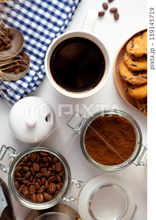 White cup of coffee top view. Ground coffee and grain. Breakfast is on the table. Coffee background. An invigorating drink still life. Food at home. White cup of coffee top view. Ground coffee and grain. Breakfast is on the table. Coffee background. An invigorating drink still life. Food at home. 139145719