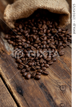 Bag of coffee on a wooden table. Coffee beans are poured. Top view, place for text. Coffee background. Food and drink. Bag of coffee on a wooden table. Coffee beans are poured. Top view, place for text. Coffee background. Food and drink. 139145725