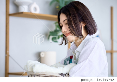 穏やかな笑顔で洗濯物を畳む若い女性のライフスタイル 穏やかな笑顔で洗濯物を畳む若い女性のライフスタイル 139145742