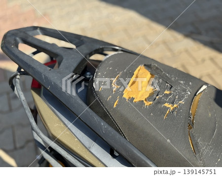 Damaged motorcycle seat with visible tears and cracks on a sunny day Damaged motorcycle seat with visible tears and cracks on a sunny day 139145751