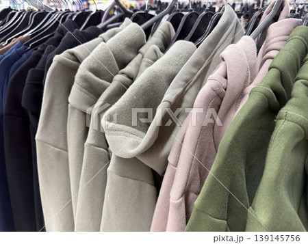 Hoodies on hangers in clothing store display various colors and styles for casual fashion shoppers Hoodies on hangers in clothing store display various colors and styles for casual fashion shoppers 139145756
