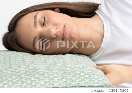 Young woman sleeping peacefully on green pillow indoor Young woman sleeping peacefully on green pillow indoor 139145801