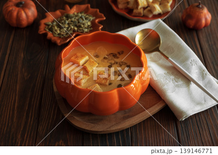 Creamy pumpkin soup with croutons and seeds, served in a pumpkin shaped bowl 139146771
