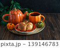 Autumnal tea set with pumpkin shaped teapot and mug, and a baked buns 139146783