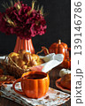 Autumnal tea set with baked buns into basket, pumpkin shaped teapot and mug 139146786