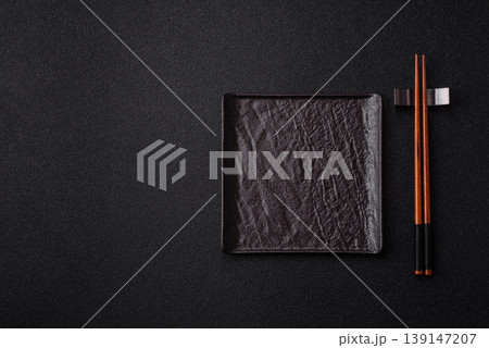 An empty ceramic square black plate with chopsticks for Asian food. An empty square plate 139147207