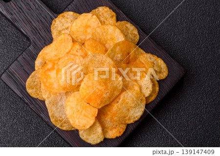 Crispy potato chips, golden slices seasoned with salt and spices. Potato chips Crispy potato chips, golden slices seasoned with salt and spices. Potato chips 139147409