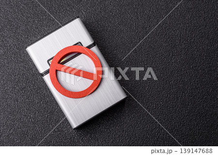 A metal cigarette box with a no smoking sign depicts a harmful habit. A cigarette box A metal cigarette box with a no smoking sign depicts a harmful habit. A cigarette box 139147688