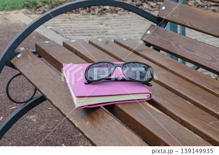 Sunglasses On Notebook On Wooden Park Bench Sunglasses On Notebook On Wooden Park Bench 139149935