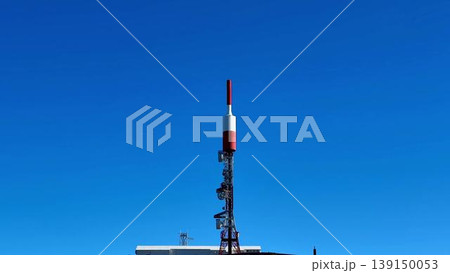 A striking red, white, and blue antenna tower atop a hill symbolizes technology A striking red, white, and blue antenna tower atop a hill symbolizes technology 139150053