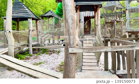 A wooden playground with a green slide and rope bridge for kids 139150073