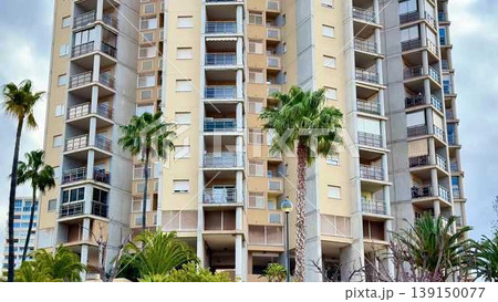 Video shows a tall apartment building with palm trees and life Video shows a tall apartment building with palm trees and life 139150077