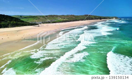 A beautiful beach with stunning waves and surfers enjoying a sunny day by the ocean A beautiful beach with stunning waves and surfers enjoying a sunny day by the ocean 139150134
