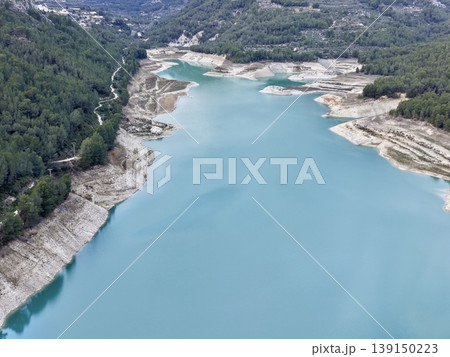 Bright turquoise water extending over land, Elevated view of colorful lake amidst greenery and rocks 139150223