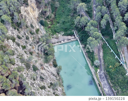 Cliffside water collection system adjacent to vibrant turquoise reservoir and utility inspection route Cliffside water collection system adjacent to vibrant turquoise reservoir and utility inspection route 139150228