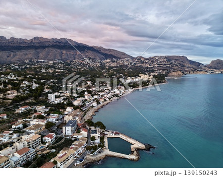 Evening hues brighten peaceful coastal settlements, Sunset hues fill calm seaside towns and rolling hills 139150243