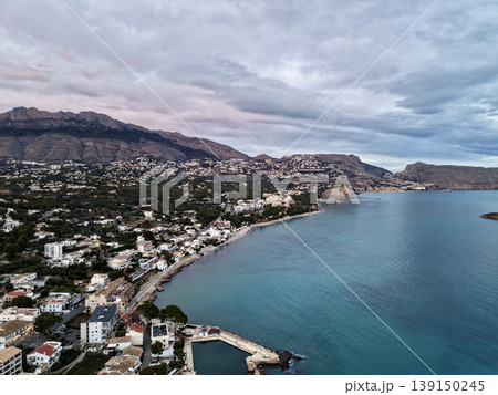 Elevated image capturing serene neighborhood with turquoise waters and mountain scenery under cloudy sky 139150245