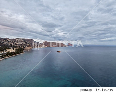 Gloomy ocean scene, Misty sky above tranquil waters featuring isolated rocky formation and gentle waves Gloomy ocean scene, Misty sky above tranquil waters featuring isolated rocky formation and gentle waves 139150249