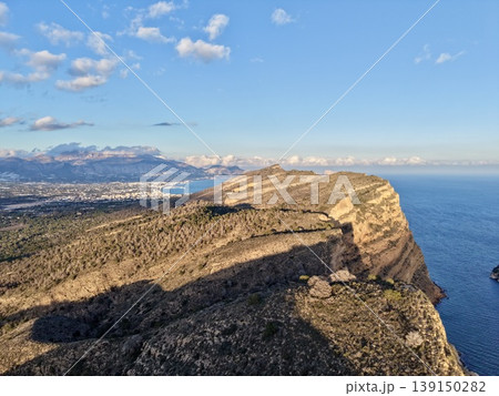 Mountain vista serenity, Cliffside view with peaceful waters, Sunset over rugged coast with shadowed rocks 139150282