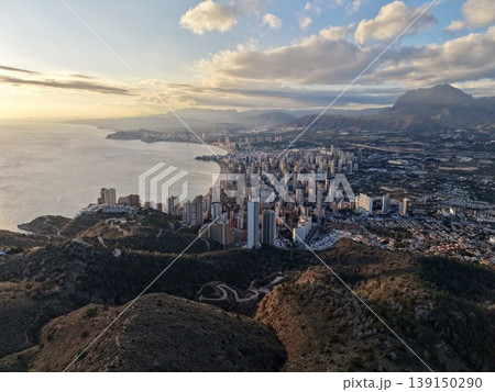 Urban sunset view, Metropolitan horizon illuminated with shimmering lights and scenic mountains 139150290