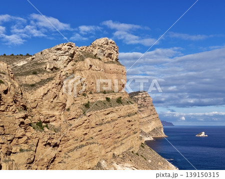 Sunny coastal cliffs with ferry and waves, Majestic sandstone cliffs overlooking calm sea with ferry nearby 139150315