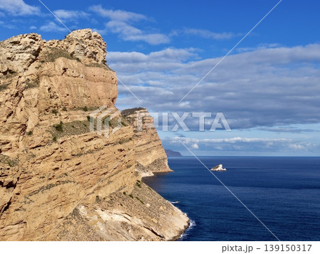 Majestic cliff with lone vessel, Expansive ocean scene with distant boat and layered cliffs Majestic cliff with lone vessel, Expansive ocean scene with distant boat and layered cliffs 139150317