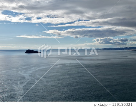 Isolated island scene, Remote and rugged island surrounded by peaceful water and distant shoreline views Isolated island scene, Remote and rugged island surrounded by peaceful water and distant shoreline views 139150321