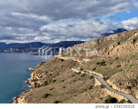 Spectacular coastal pathway showcasing rugged cliffs beside bustling city bay under dramatic clouds Spectacular coastal pathway showcasing rugged cliffs beside bustling city bay under dramatic clouds 139150328