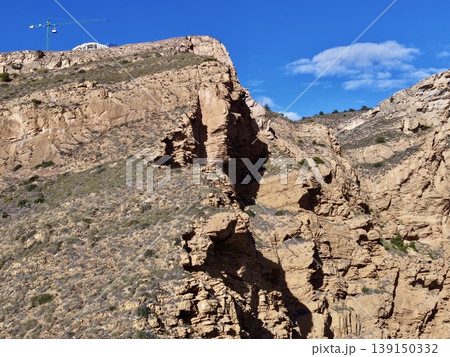 Vivid sunset casts warm light on rugged geological formations near tranquil coastal horizons 139150332