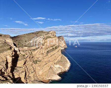 Alone boat by vast sea, Isolated high point overlooking open water and lone vessel under clear sky 139150337