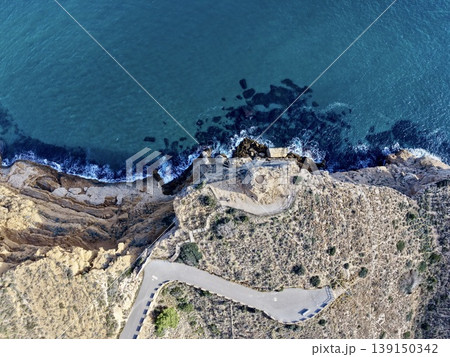 Highaltitude footpath winding near rocky coastlines with viewing platform and shimmering turquoise sea 139150342