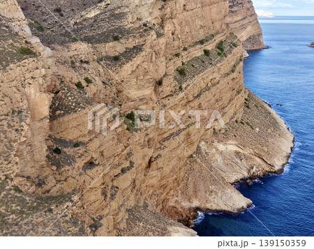 Shoreline caves and vibrant water scenes, Closeup of colorful rocky coves and deep ocean blue hues 139150359