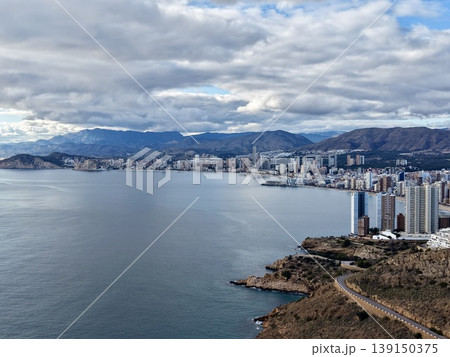 Skyscrapers gaze over tranquil bay, Contemporary highrise buildings face peaceful bay with mountains 139150375