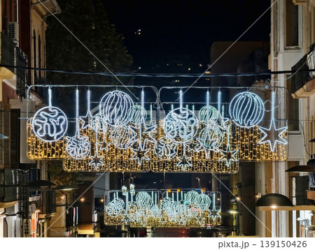 Evening decorations adorn bustling street. Nighttime cityscape illuminated by decorative fixtures 139150426