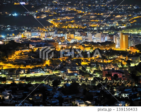 Quiet evening scene featuring densely built structures and illuminated streets across hills Quiet evening scene featuring densely built structures and illuminated streets across hills 139150433
