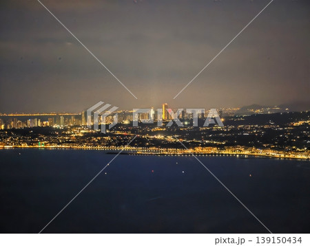 Calm coast at dusk scene. Serene twilight shoreline displaying luminous lights and still waters Calm coast at dusk scene. Serene twilight shoreline displaying luminous lights and still waters 139150434