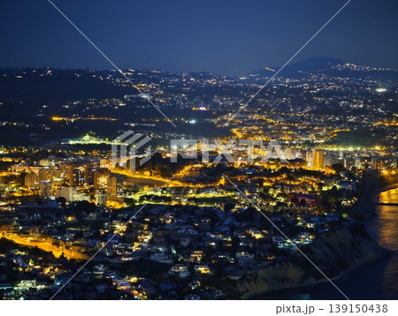 Panoramic view of seaside city at night with bright ribbons illuminating streets and shoreline Panoramic view of seaside city at night with bright ribbons illuminating streets and shoreline 139150438