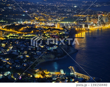 Town by bay illuminated under starlight. Lights from homes and piers cast tranquil glow over bay Town by bay illuminated under starlight. Lights from homes and piers cast tranquil glow over bay 139150440