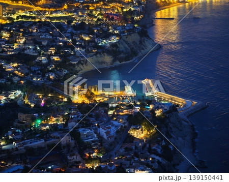 Idyllic coastal setting at night featuring illuminated structures and serene water reflections Idyllic coastal setting at night featuring illuminated structures and serene water reflections 139150441