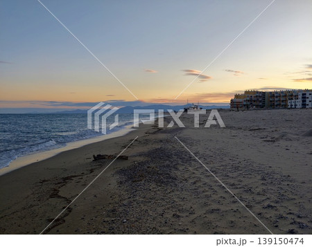 Coastal apartments by waves. Sunset at coastal retreat with highrise apartments and soothing ocean waves 139150474