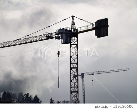 Gloomy metropolitan skyline shaded by clouds with cranes and steel frameworks illustrating development Gloomy metropolitan skyline shaded by clouds with cranes and steel frameworks illustrating development 139150500