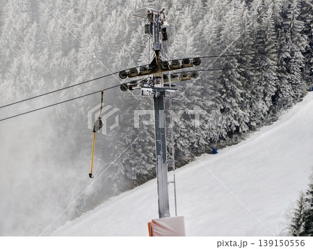 Calm winter landscape with lift and snow. Quiet snowcovered hill featuring lift pole and distant trees Calm winter landscape with lift and snow. Quiet snowcovered hill featuring lift pole and distant trees 139150556