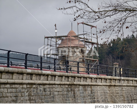 Ancient masonry being repaired near water. Renovation of historic damside stonework with scaffolding 139150782